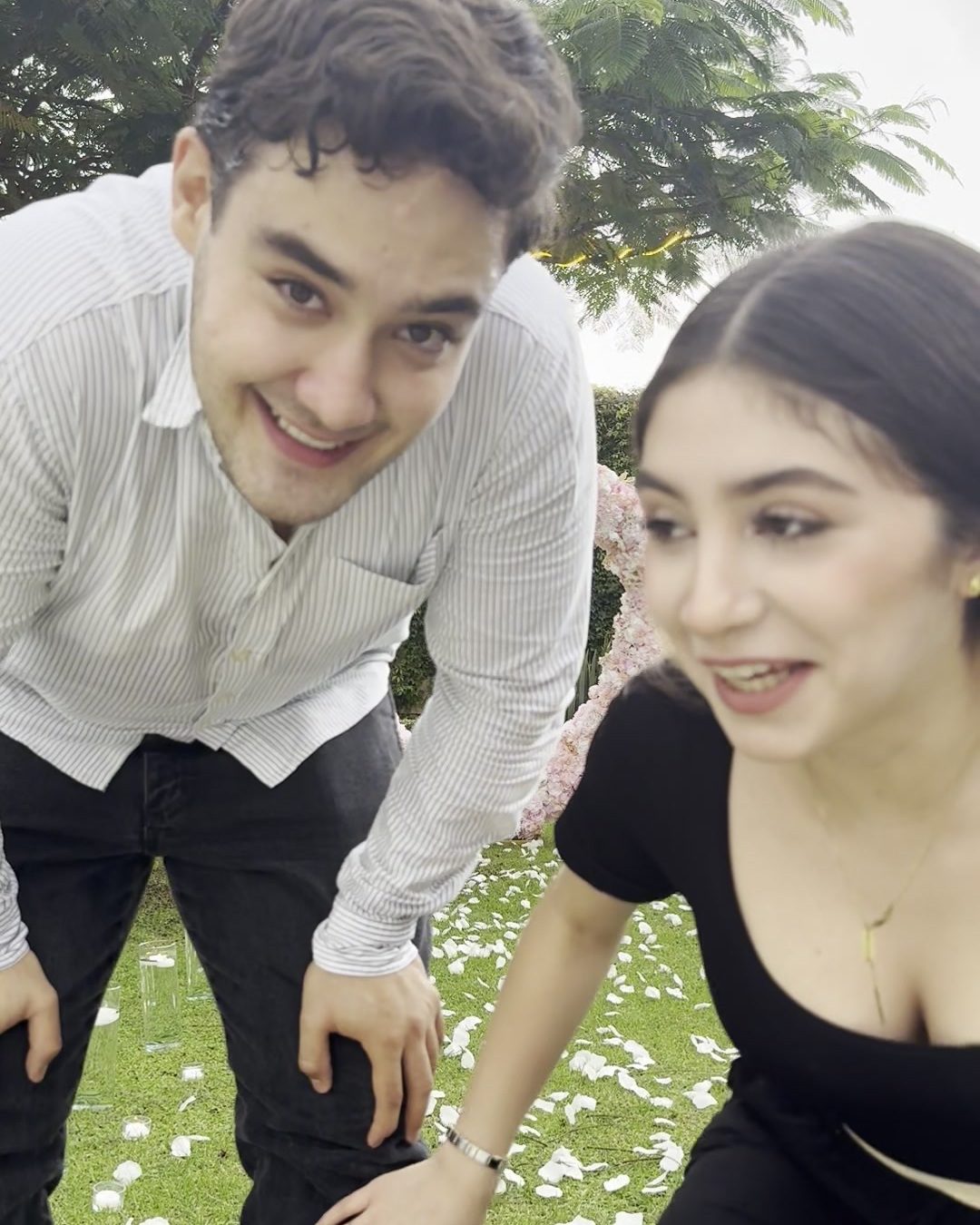 La pareja riéndose frente al corazón de flores después de la propuesta
